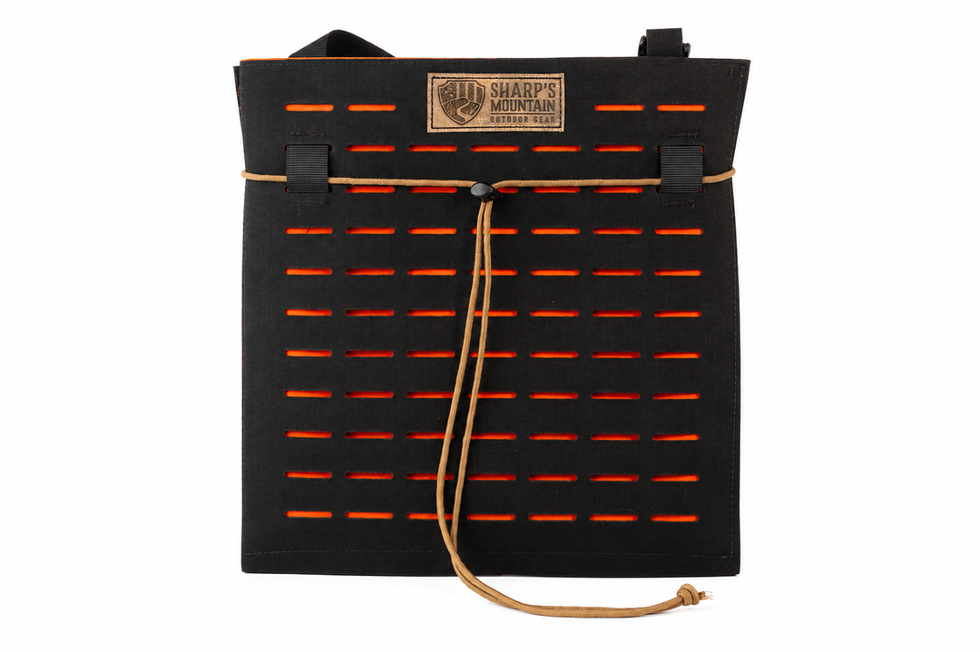 A black Sharp's Mountain Range office with orange horizontal cutouts, tan paracord strap, and a tan brand patch on the front, shown against a plain white background.
